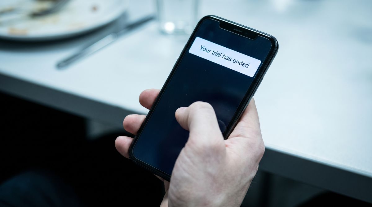 Hand gripping phone showing trial ended notification